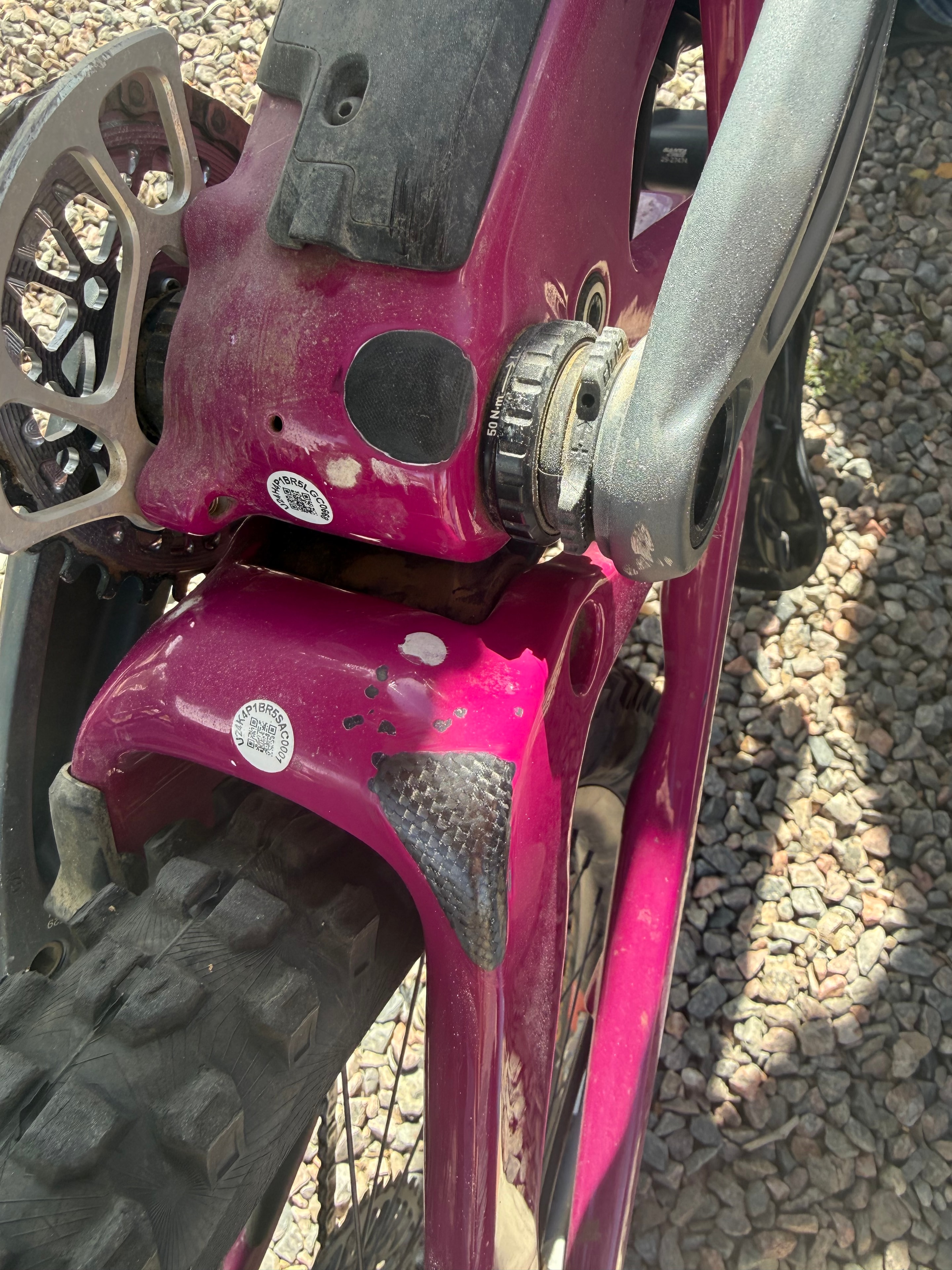 Carbon fiber bottom bracket repair on a magenta mountain bike frame with woven carbon patch