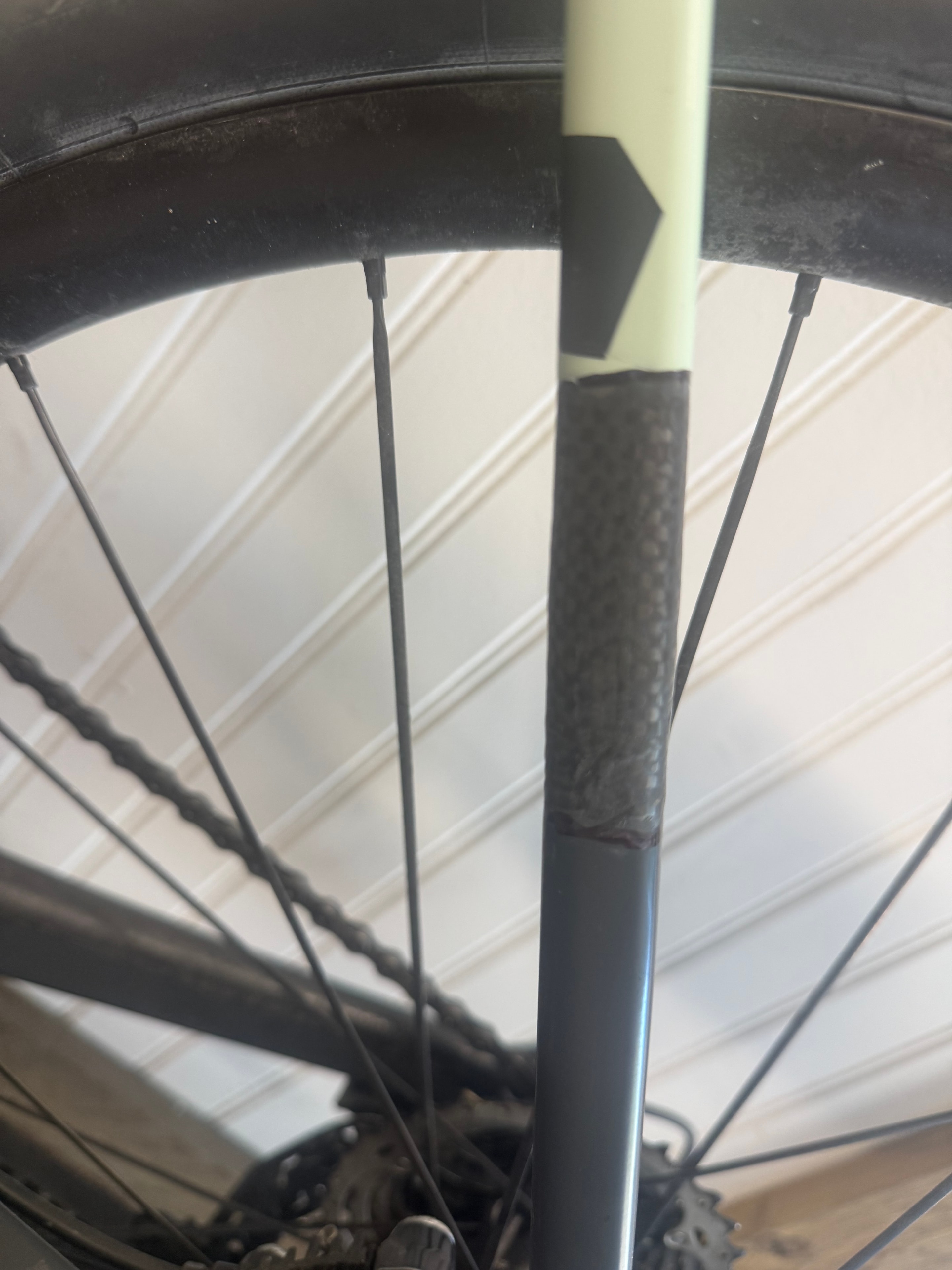 Carbon fiber seat stay repair on a sage green bike — close-up of woven carbon patch