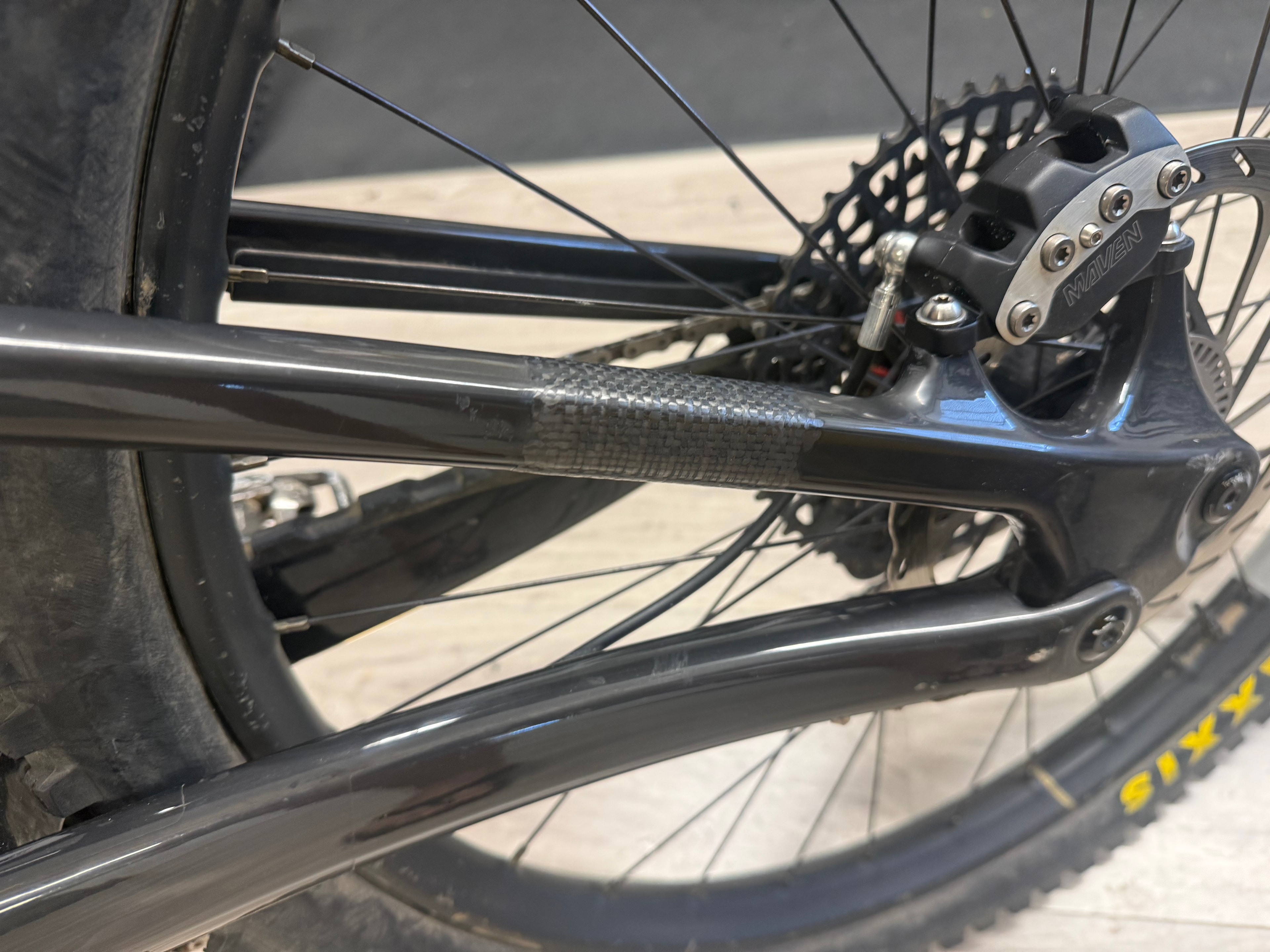 Carbon fiber seat stay repair on a black mountain bike with Maven brakes and SIXX tire