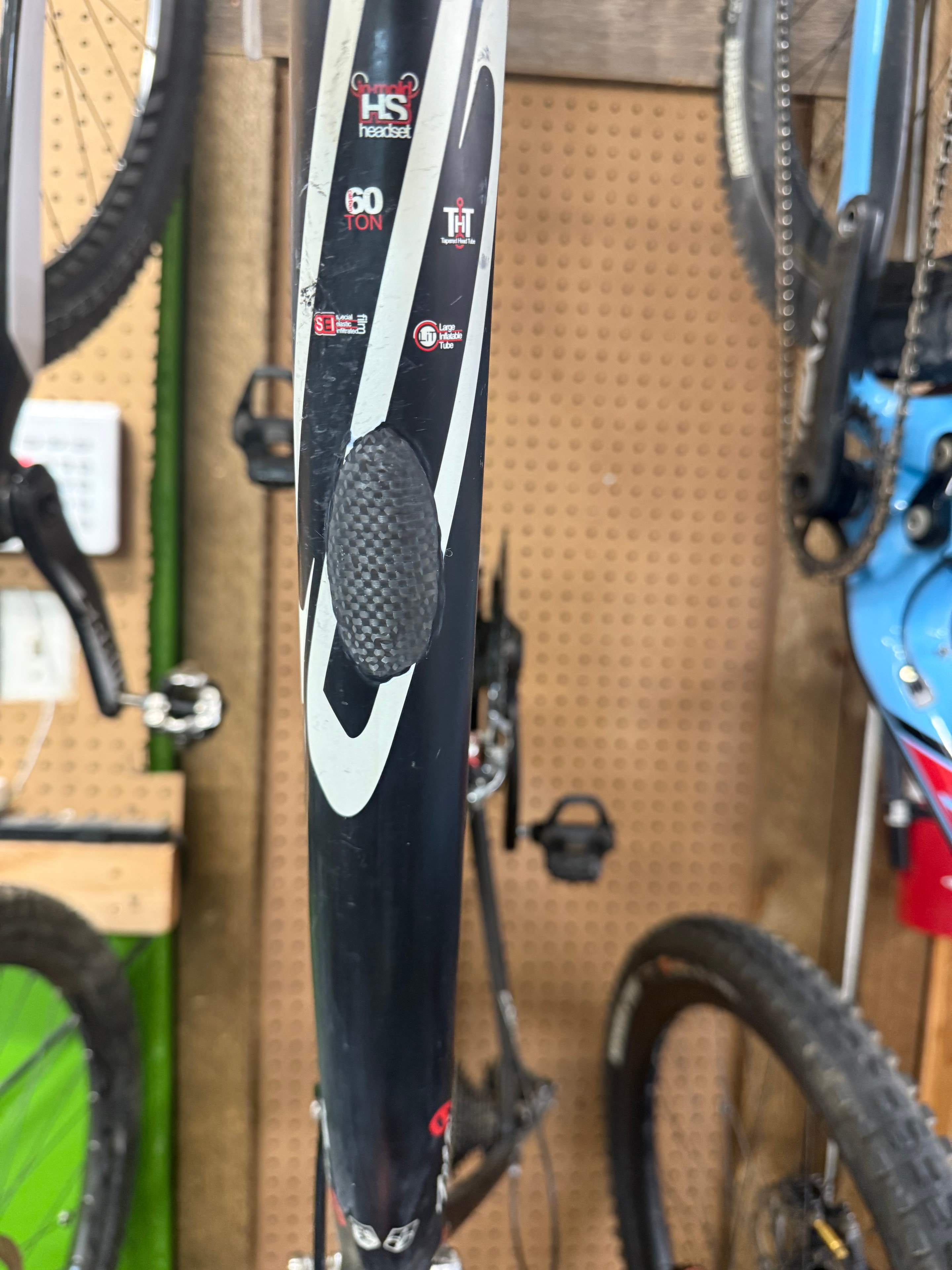 Carbon fiber top tube repair on a black frame with oval carbon patch